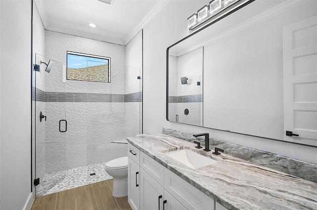 full bath with wood finished floors, toilet, vanity, a stall shower, and crown molding