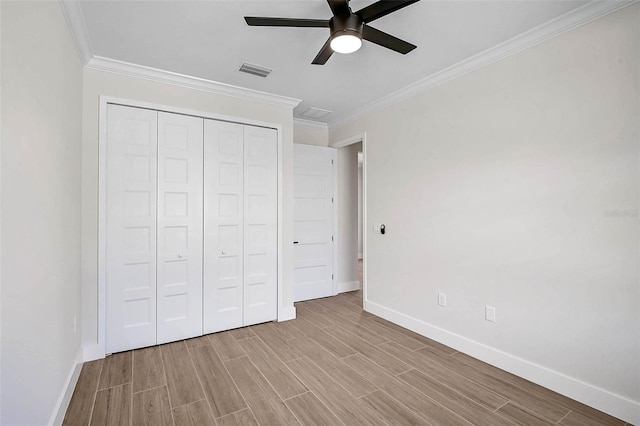 unfurnished bedroom featuring baseboards, visible vents, wood finished floors, and crown molding