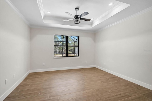empty room featuring a raised ceiling, wood finished floors, and baseboards