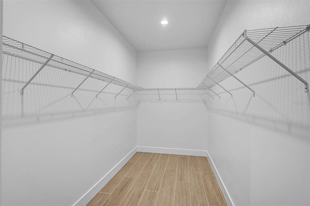 walk in closet with light wood finished floors