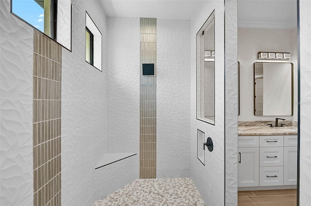 full bath featuring tiled shower and vanity