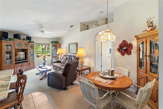 living room featuring arched walkways, light colored carpet, visible vents, a ceiling fan, and high vaulted ceiling