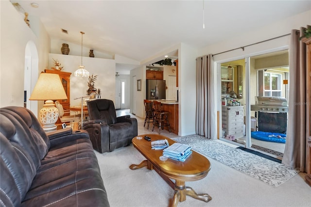 living room with arched walkways, visible vents, vaulted ceiling, and light colored carpet