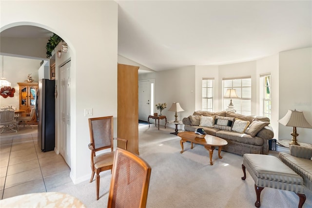 living room featuring light colored carpet, baseboards, light tile patterned flooring, and arched walkways