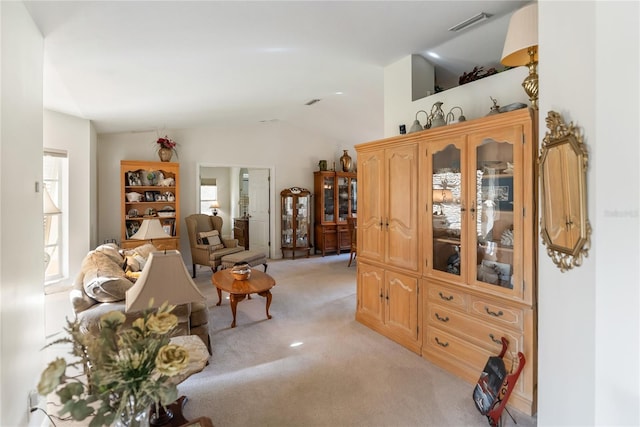 living room featuring visible vents, light colored carpet, lofted ceiling, and plenty of natural light