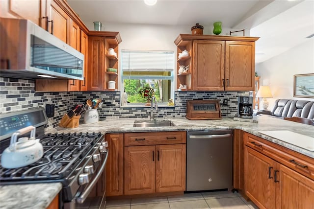 kitchen with tasteful backsplash, open shelves, a sink, stainless steel appliances, and brown cabinetry