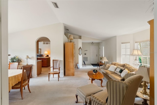 living room featuring visible vents, arched walkways, light carpet, and lofted ceiling