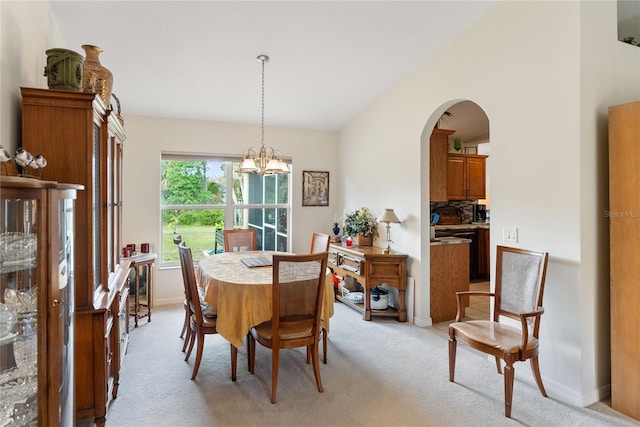 dining area with a chandelier, light carpet, baseboards, and arched walkways