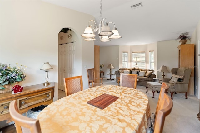 dining space with lofted ceiling, light colored carpet, visible vents, and a notable chandelier