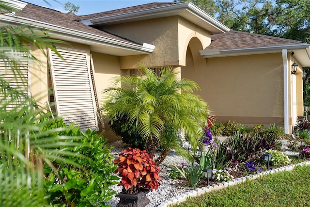 view of home's exterior with stucco siding and roof with shingles