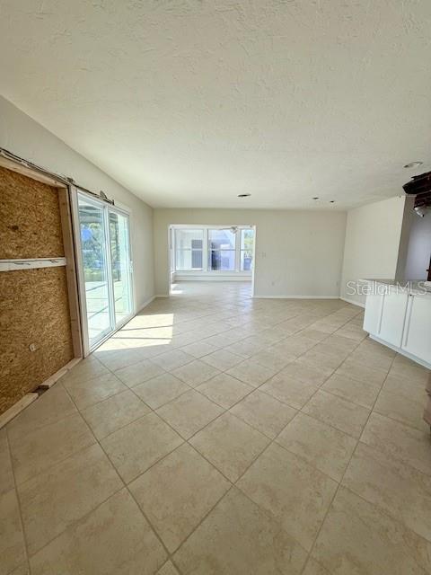 unfurnished room featuring light tile patterned floors, a textured ceiling, and plenty of natural light