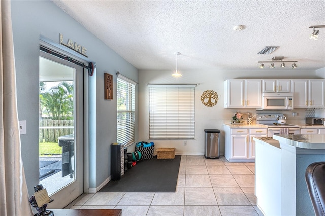 12026 Warwick Cir, Parrish, FL 34219 - kitchen with white appliances, white cabinetry, a textured ceiling, light tile patterned floors, and pendant lighting