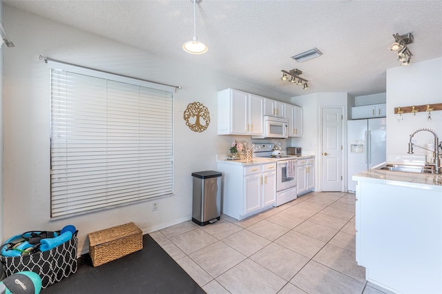 12026 Warwick Cir, Parrish, FL 34219 - kitchen with white appliances, white cabinets, a textured ceiling, light countertops, and light tile patterned floors