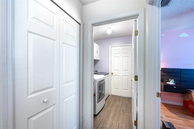 12026 Warwick Cir, Parrish, FL 34219 - laundry area with cabinet space, a textured ceiling, washing machine and clothes dryer, and light wood-style flooring