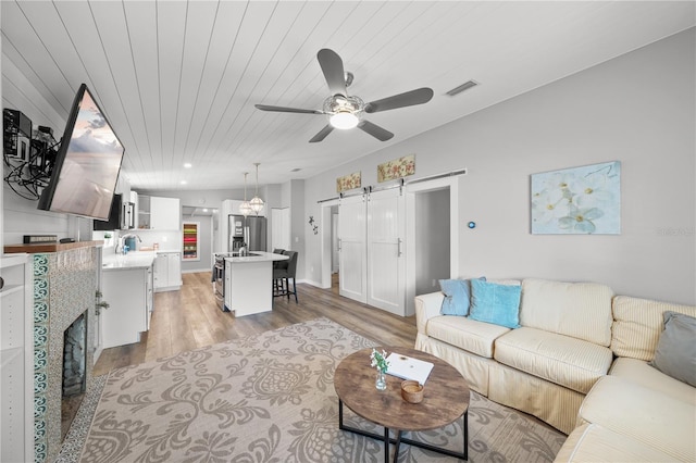 2537 Ashton Rd, Sarasota, FL 34231 - living area featuring light wood-style flooring, wood ceiling, a barn door, visible vents, and a ceiling fan