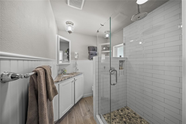2537 Ashton Rd, Sarasota, FL 34231 - full bathroom featuring hardwood / wood-style floors, visible vents, a stall shower, and wainscoting