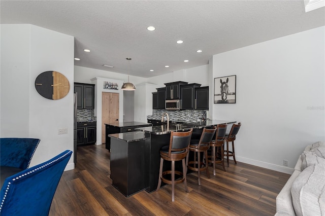 3806 155th Ave E, Parrish, FL 34219 - kitchen featuring decorative backsplash, dark wood finished floors, a kitchen bar, dark cabinetry, and recessed lighting
