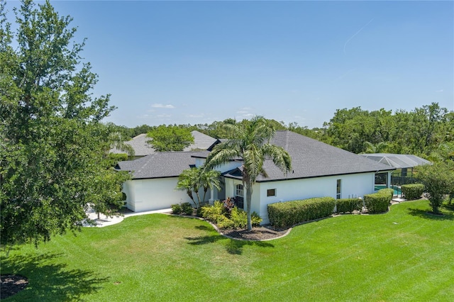 3806 155th Ave E, Parrish, FL 34219 - view of home's exterior with stucco siding, roof with shingles, a yard, and a lanai