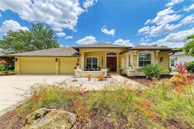 view of front of home with driveway, french doors, an attached garage, stone siding, and stucco siding