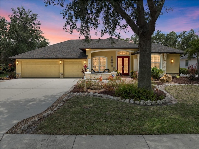 single story home with a garage, stucco siding, and french doors