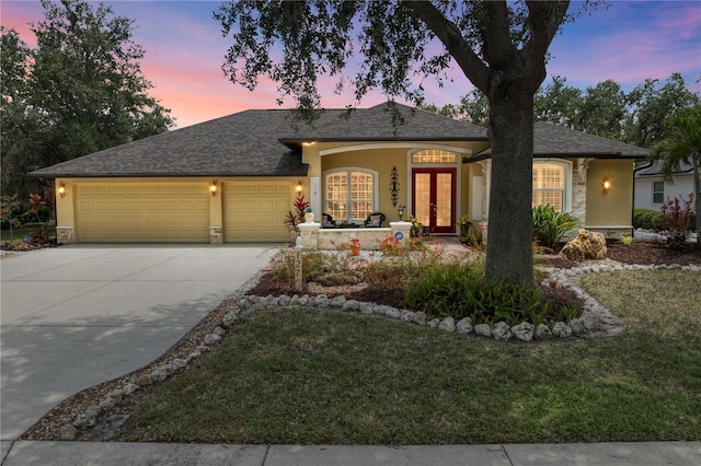 single story home featuring an attached garage, stucco siding, and french doors