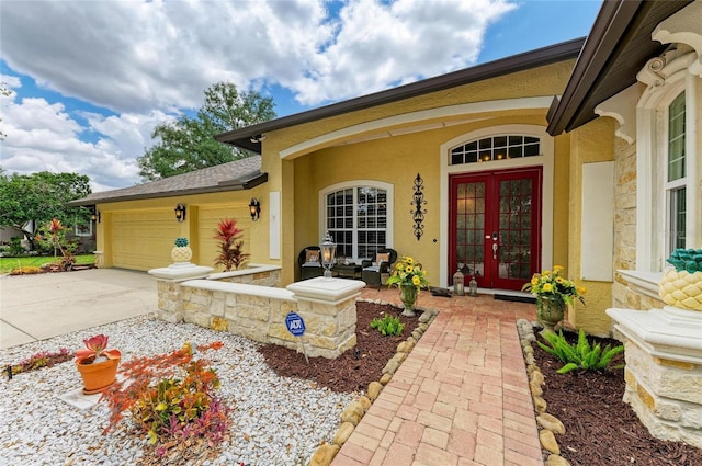 property entrance with a garage, covered porch, stucco siding, french doors, and concrete driveway