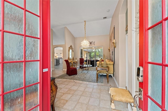 entrance foyer featuring arched walkways, tile patterned flooring, baseboards, high vaulted ceiling, and a notable chandelier