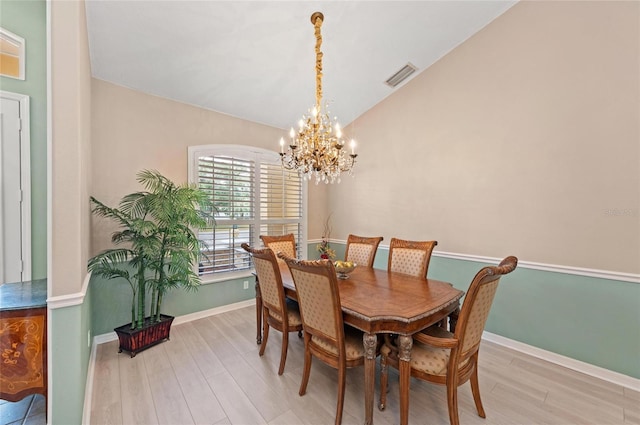 dining space featuring visible vents, baseboards, a chandelier, lofted ceiling, and light wood-style flooring