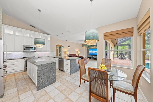 kitchen with an inviting chandelier, a peninsula, a sink, and appliances with stainless steel finishes