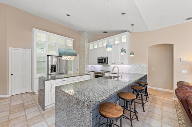 kitchen featuring decorative backsplash, a peninsula, arched walkways, a sink, and stainless steel appliances