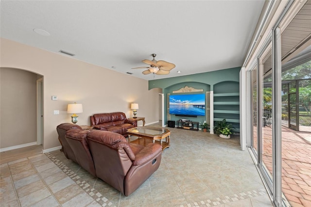 living area with arched walkways, a ceiling fan, visible vents, and baseboards