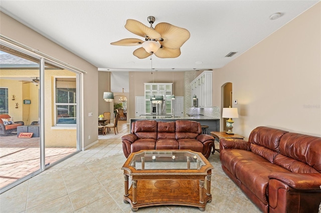 living area featuring a ceiling fan, arched walkways, visible vents, and light tile patterned floors