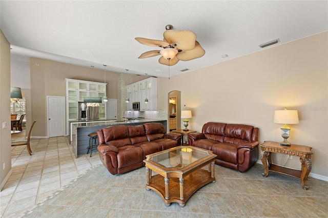 living area featuring visible vents, arched walkways, baseboards, and ceiling fan