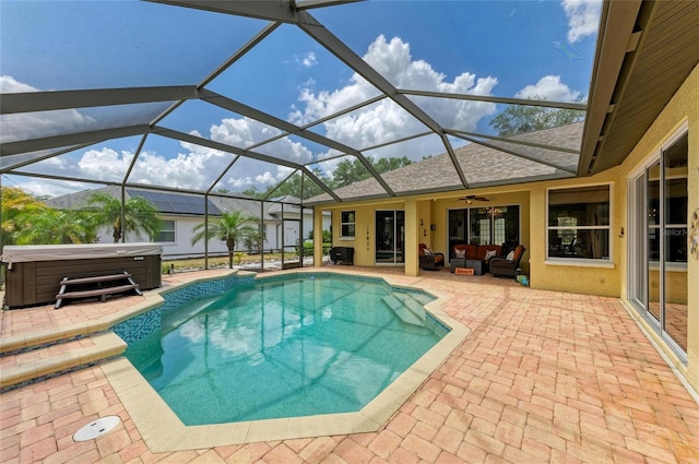 pool featuring outdoor lounge area, a patio, a ceiling fan, glass enclosure, and a hot tub