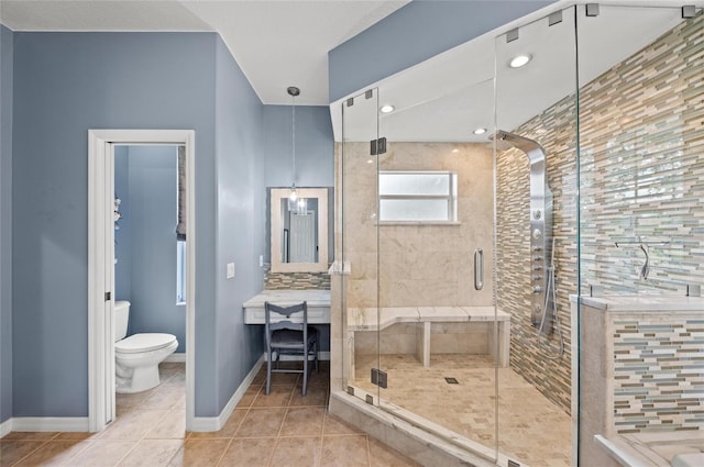 bathroom with tile patterned floors, baseboards, a shower stall, and toilet