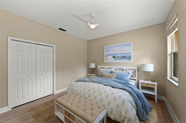 bedroom with baseboards, visible vents, wood finished floors, and a closet