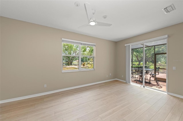 empty room featuring baseboards, a ceiling fan, light wood-type flooring, and visible vents