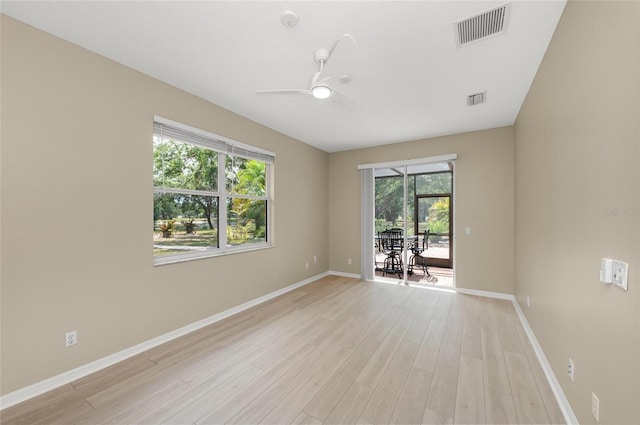 empty room with baseboards, ceiling fan, light wood-type flooring, and visible vents
