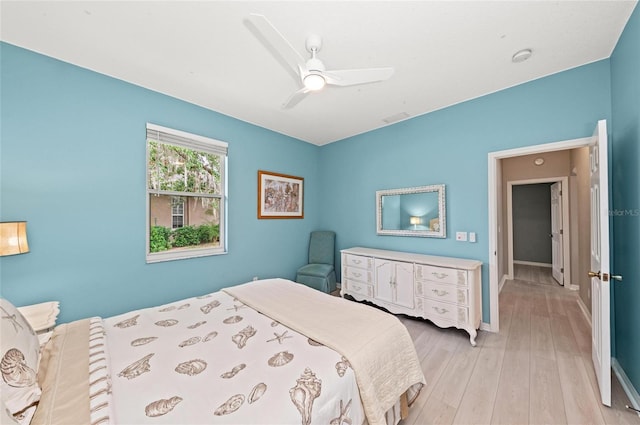 bedroom with a ceiling fan, baseboards, visible vents, and light wood-style flooring