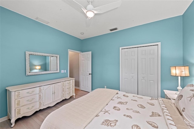 bedroom with visible vents, ceiling fan, wood finished floors, and a closet