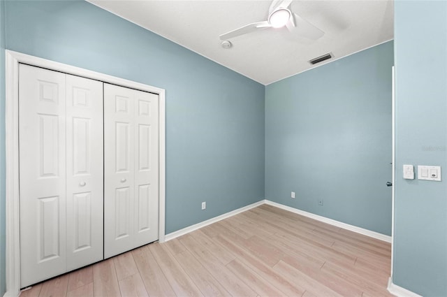 unfurnished bedroom with a ceiling fan, baseboards, wood finished floors, visible vents, and a closet