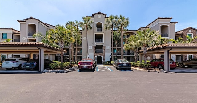view of building exterior with covered and uncovered parking