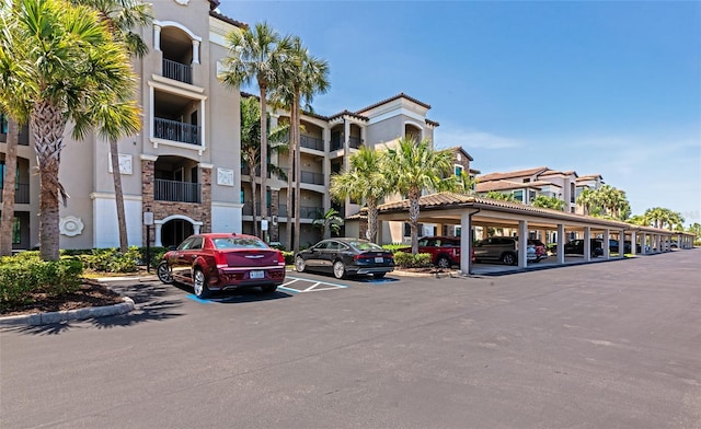 view of building exterior featuring covered and uncovered parking