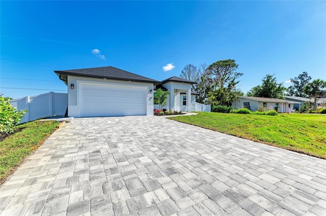 view of front of house with fence, decorative driveway, a front lawn, and a garage