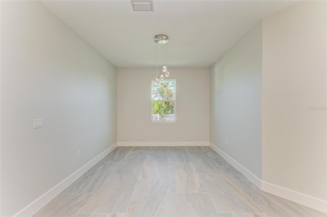 empty room featuring marble finish floor, visible vents, a chandelier, and baseboards