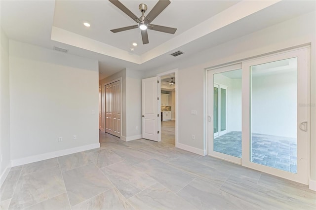 unfurnished bedroom featuring recessed lighting, visible vents, a raised ceiling, and baseboards