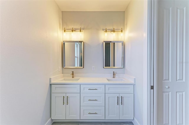 full bath featuring baseboards, double vanity, and a sink