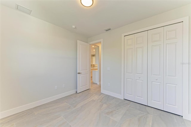 unfurnished bedroom with visible vents, a closet, and baseboards