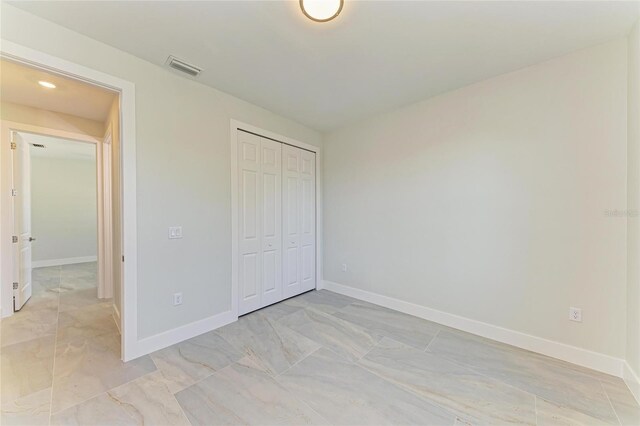 unfurnished bedroom featuring a closet, marble finish floor, and baseboards