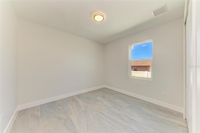 unfurnished room with baseboards and visible vents